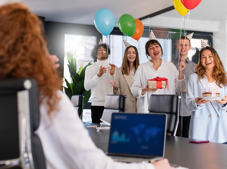 Collega's vieren samen een verjaardag op kantoor met een taart met kaarsjes